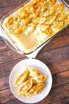 a casserole dish with chicken and cheese in it next to a white plate on a wooden table