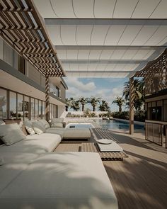 an outdoor living area with white couches and tables next to a swimming pool in the background