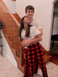 a young man and woman standing next to each other in front of a stair case