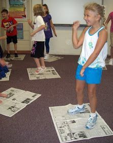 a group of young children standing on top of newspapers in front of a whiteboard