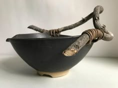 a black bowl with two sticks sticking out of it's sides, on a white surface