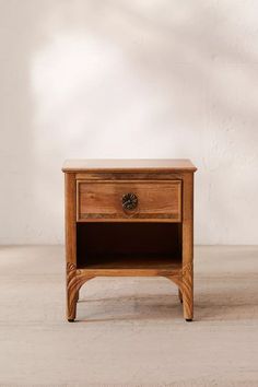 a small wooden table with a drawer on it's side and a white wall in the background