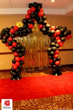 a star shaped balloon arch with red, black and white balloons on it in the middle of a carpeted room