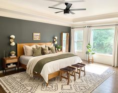 a bedroom with a bed, two stools and a rug on the floor in front of a window