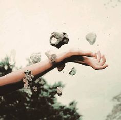 a woman's arm with rocks falling from it