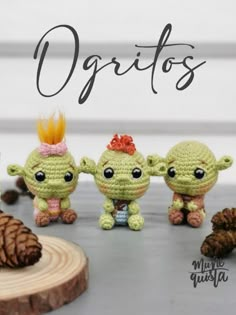 three crocheted dolls are standing next to a pine cone with the words ogritos written on it