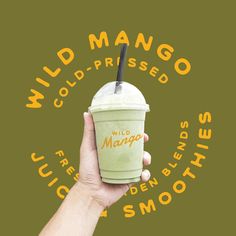 a hand holding up a green drink with the words wild mango and custard on it