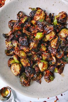 brussel sprouts on a white plate next to silverware and spoons