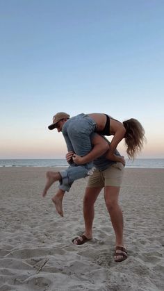 a man is holding a woman on the beach