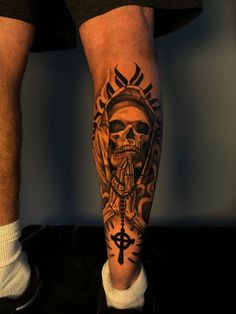 a man's leg with a skull and cross tattoo on it