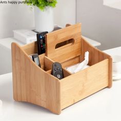 a wooden holder with remotes and cell phones in it sitting on a white table