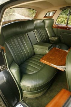 the interior of an old car with green leather seats and wood table in center console