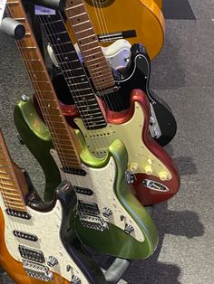 guitars are lined up on display in a row, all different colors and sizes with their heads facing the same direction