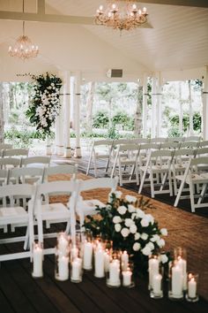 an outdoor wedding venue with white chairs and candles