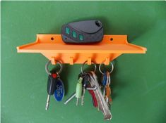 an orange shelf with keys and car keys hanging from it's hooks on a green wall