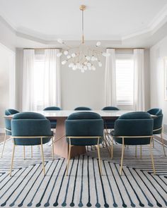 a dining room table with blue chairs and a chandelier