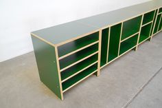 a green shelf with several compartments on top and two doors open to reveal the shelves