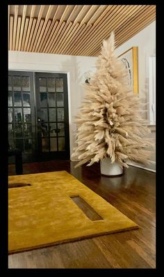 a white christmas tree sitting on top of a wooden floor next to a door way