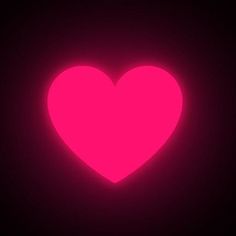 a neon pink heart in the dark with only one light shining on it's side