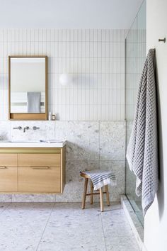 a bathroom with two sinks, a mirror and a stool in the middle of it