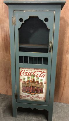 an old blue cabinet with coca cola painted on it