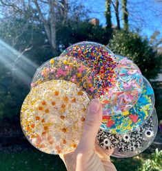 a person holding up two plates with sprinkles on them in the sun