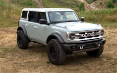 a silver truck parked on top of a dirt field