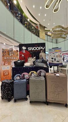 several pieces of luggage are on display in a store with an advertisement for snoopy