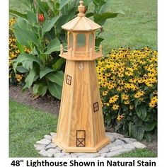 a wooden light house sitting in the middle of a flower garden next to some yellow flowers