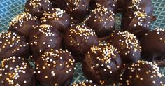 chocolate covered donuts with gold sprinkles on a green mesh tablecloth