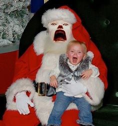 a child is sitting on santa claus's lap with his mouth open and tongue out