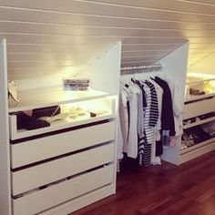 a closet with drawers and clothes hanging on the wall