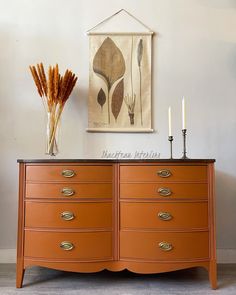 an orange dresser with three candles on top