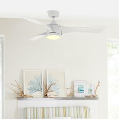 a white ceiling fan sitting above a bed in a bedroom next to pictures on the wall