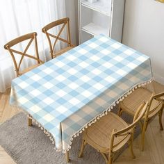 a blue and white checkered tablecloth on a dining room table with four chairs