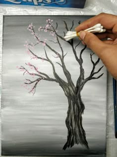 someone is painting a tree with white and pink flowers