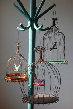 three birdcages hanging from a metal pole