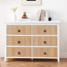 a white dresser with drawers and a teddy bear sitting on it's top shelf