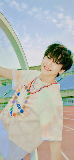 a young man standing on top of a tennis court wearing a white shirt and beaded necklace