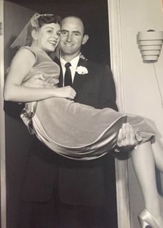 an old photo of a man and woman posing for the camera with their wedding dress draped over them