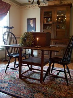 a dining room table with two chairs and a laptop on it, in front of a window