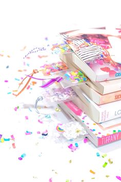 a stack of books sitting on top of each other next to confetti and streamers