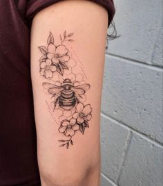 a woman's arm with flowers and a bee tattoo on the left side of her arm