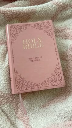 a pink bible laying on top of a blanket