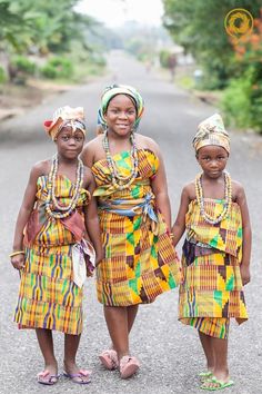 three women are standing in the middle of a road wearing colorful clothing and head wraps