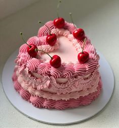 a cake with pink icing and cherries on top