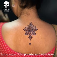 the back of a woman's neck with a lotus tattoo on her left shoulder