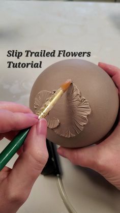 someone is painting an egg with a paintbrush and some flowers on the top it