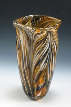 a large glass vase sitting on top of a white table next to a gray wall