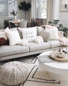 a living room filled with white furniture and lots of pillows on top of the couch